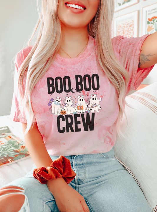 Person wearing a pink t-shirt with 'BOO BOO CREW' text and cartoon ghosts, sitting on a couch.