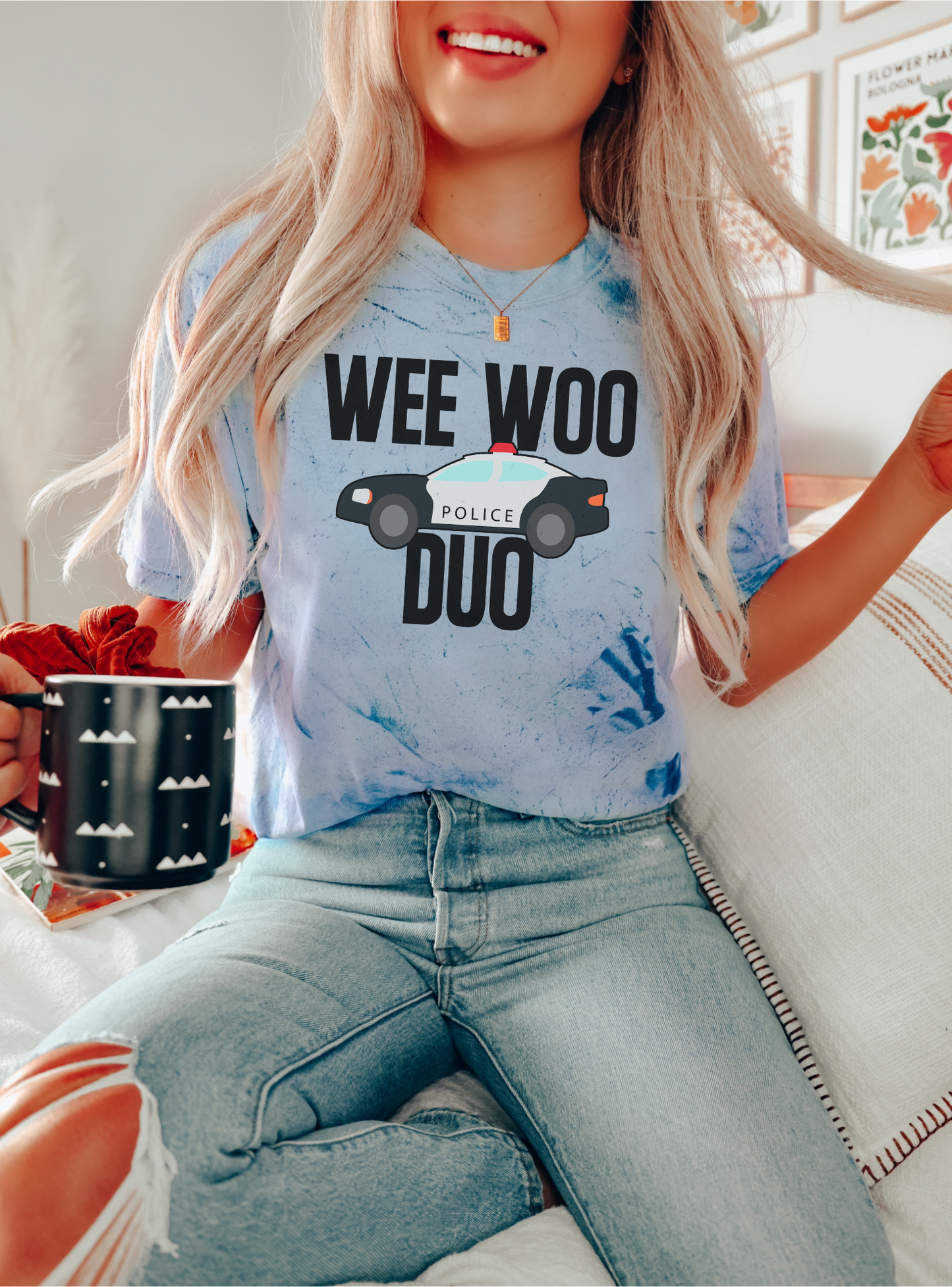 Person wearing a light blue t-shirt with 'WEE WOO POLICE DUO' text and graphic, sitting indoors.