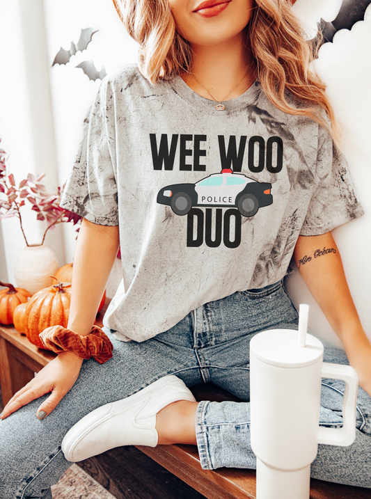 Person wearing a t-shirt with 'Wee Woo Police Duo' text and graphic, sitting indoors.