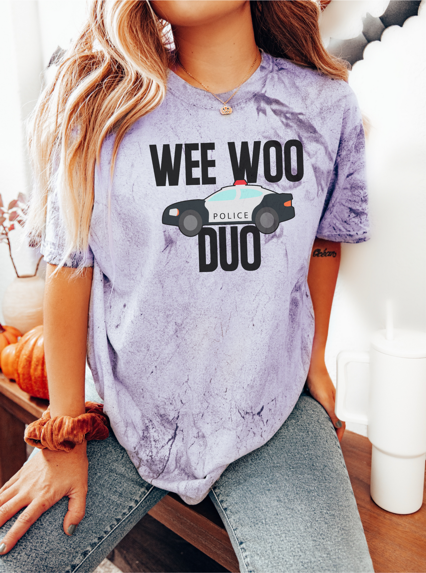 Person wearing a tie-dye t-shirt with 'WEE WOO DUO' text and police car graphic.