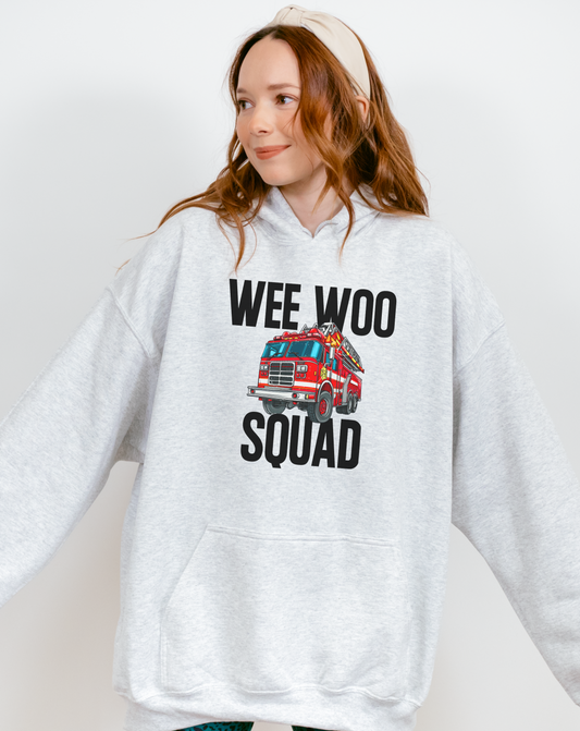 Person wearing a hoodie with 'Wee Woo Squad' and a fire truck graphic on a plain background
