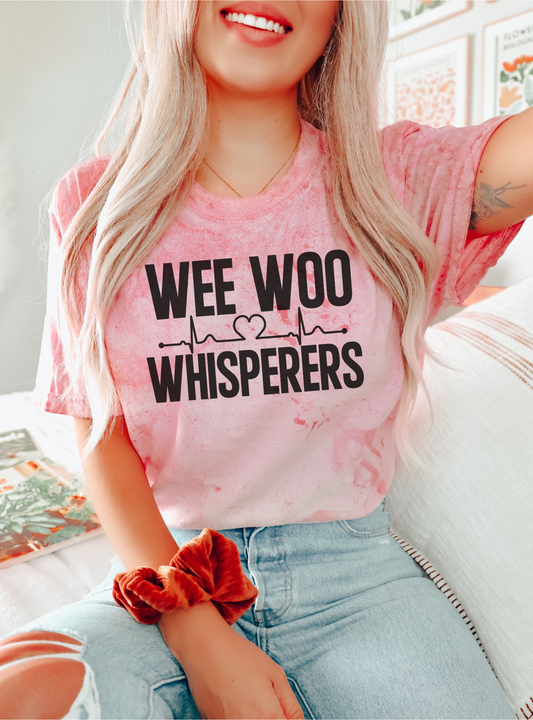 Person wearing a pink t-shirt with 'WEE WOO Whisperers' text, sitting on a couch.