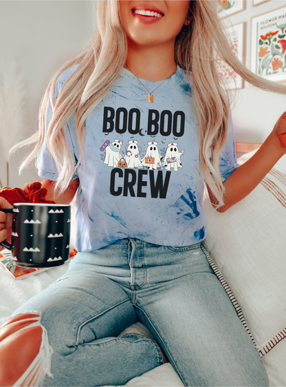 Person wearing a blue t-shirt with 'BOO BOO CREW' text and ghost graphics, sitting indoors.