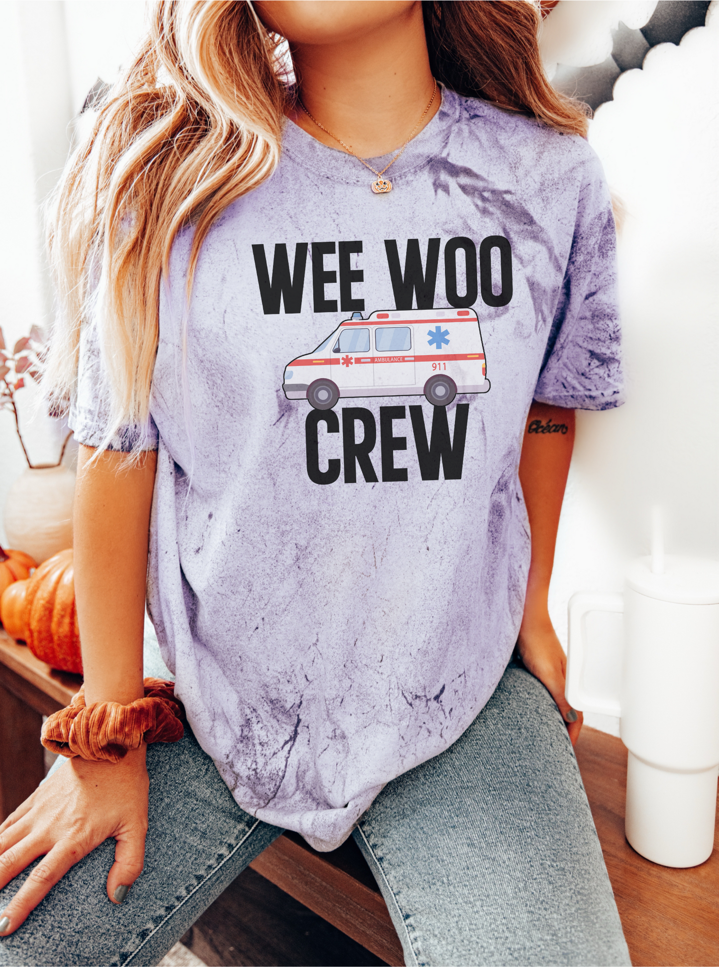 Person wearing a tie-dye t-shirt with 'WEE WOO CREW' text and ambulance graphic.